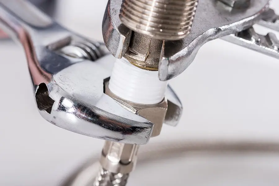 Close-up of a wrench tightening a plumbing fitting with Teflon tape | Plumbing Safety Tips for Homeowners in Cedar Hill, TX