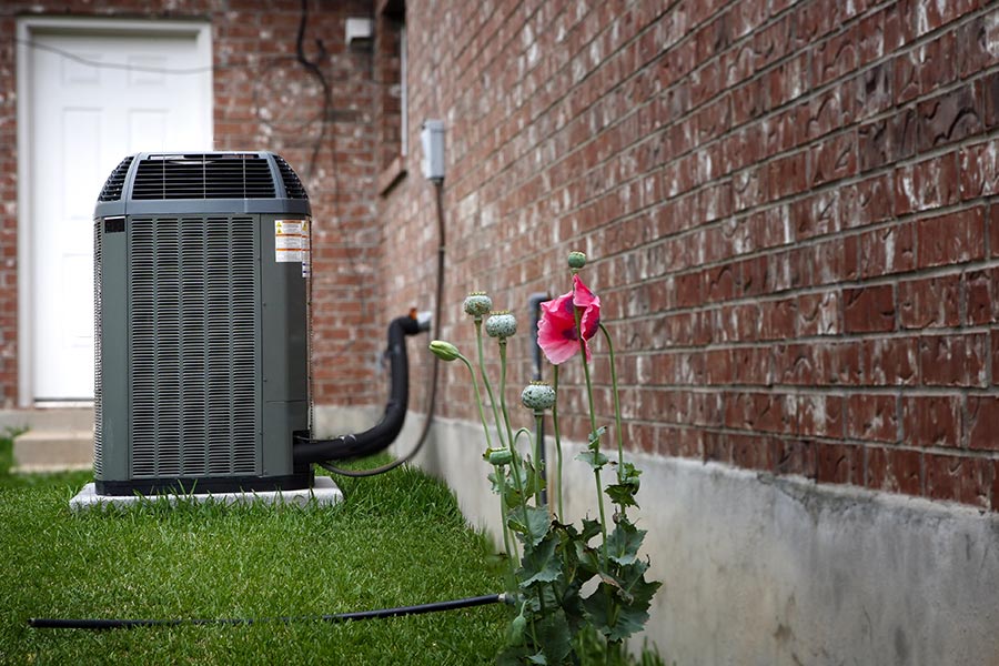 Outdoor air conditioning unit installed next to a brick house