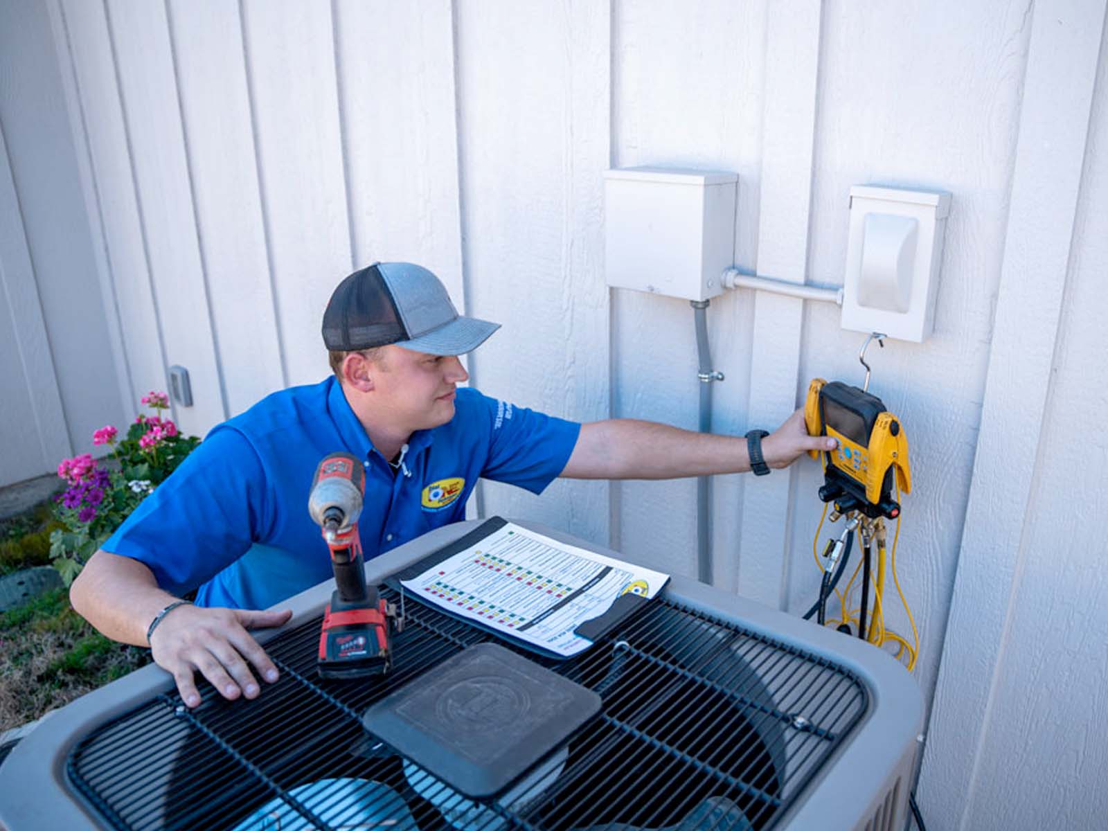 Technician using a laptop while servicing an indoor HVAC unit