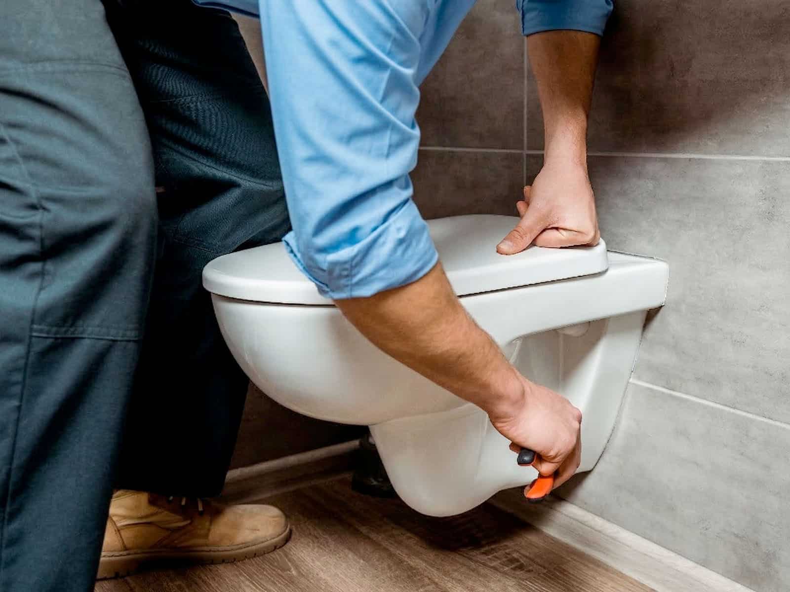 Plumber repairing a toilet in a residential bathroom
