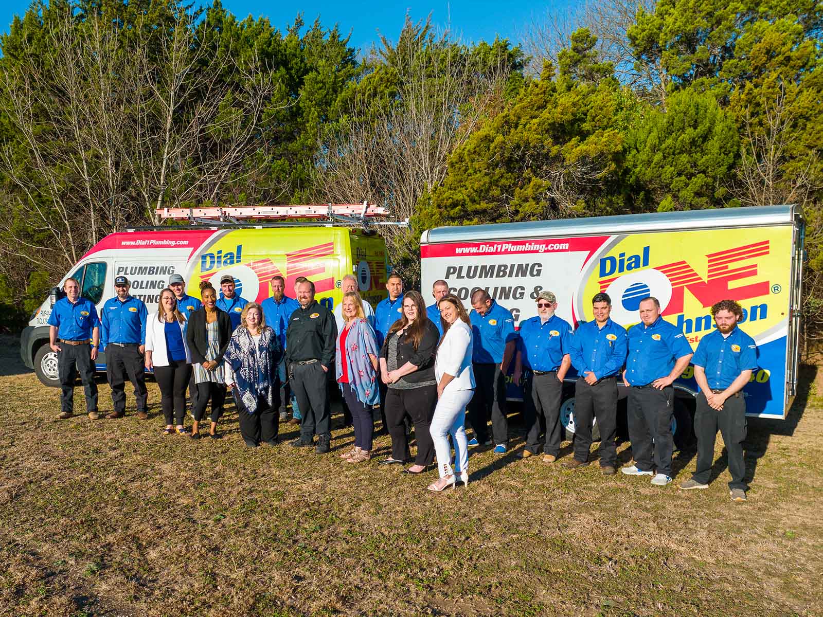 The Dial One Johnson Plumbing, Cooling & Heating team standing in front of the company's branded service trucks